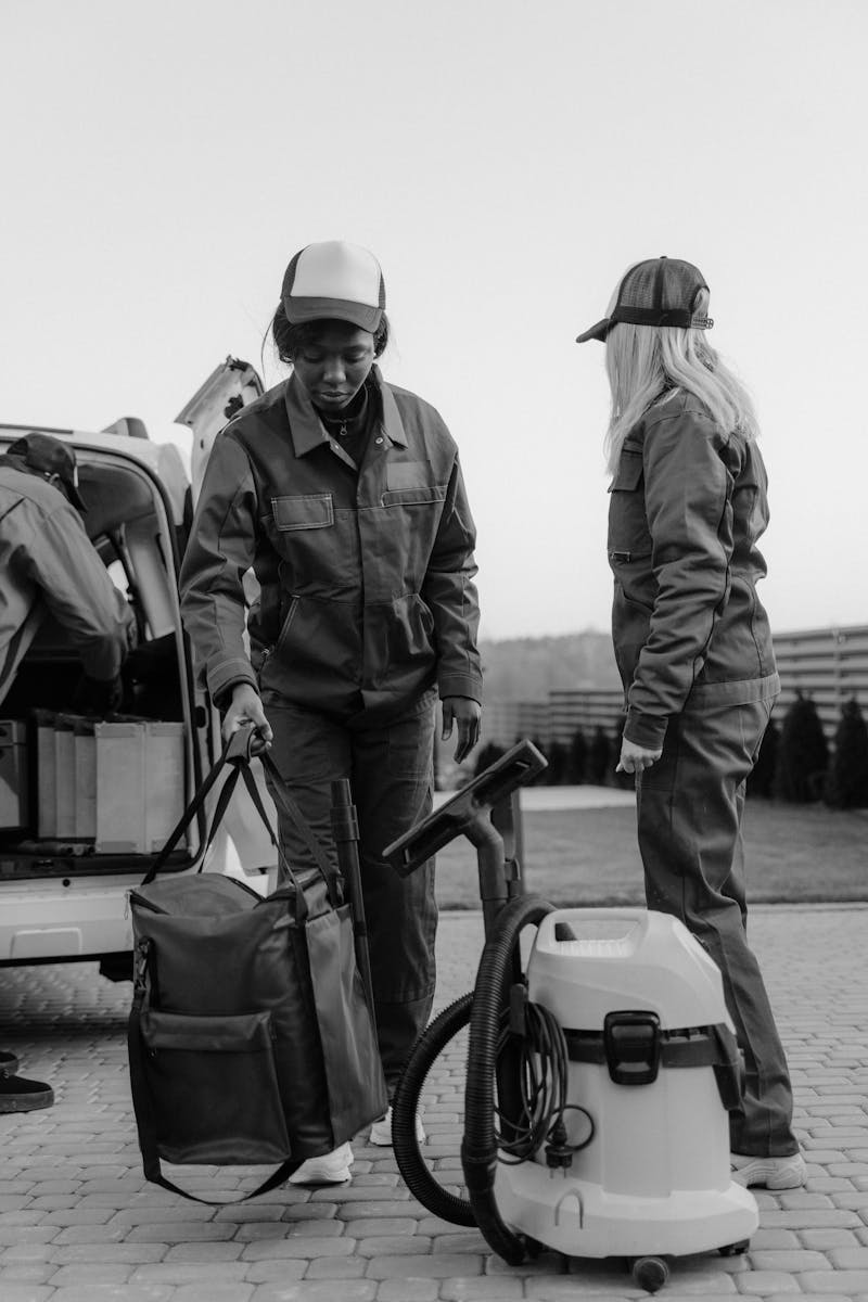 Two cleaners with equipment and van, in black and white.